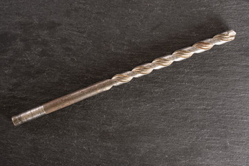 One whole metal drill work item flatlay on grey stone