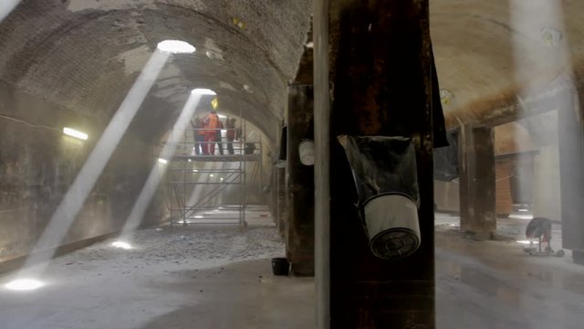 Workers in a large old water reservoir are scrapping off the ceiling wall.