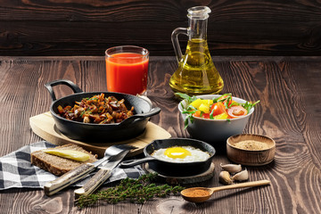 Vegetarian food. Fried mushrooms and egg in cast iron pan. Ingredients for rustic breakfast on wooden table.