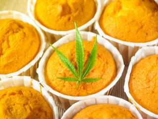 Freshly baked cinnamon mini muffins with cannabis and buds of marijuana on the table. Concept of cooking with cannabis herb. Treatment of medical marijuana for use in food.