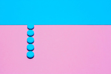 Pink and blue pills isolated on bicolor pink and blue colored background. Medication and prescription pills minimal flat lay with copy space.