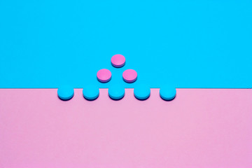 Pink and blue pills isolated on bicolor pink and blue colored background. Medication and prescription pills minimal flat lay with copy space.