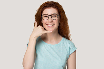 Smiling redhead girl in glasses show call phone gesture