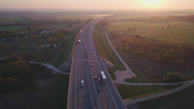 Aerial footage of a A8 highway near Wroclaw, Poland. Cars and trucks passing by during sunrise. Scenic views of fields and countryside of Poland.