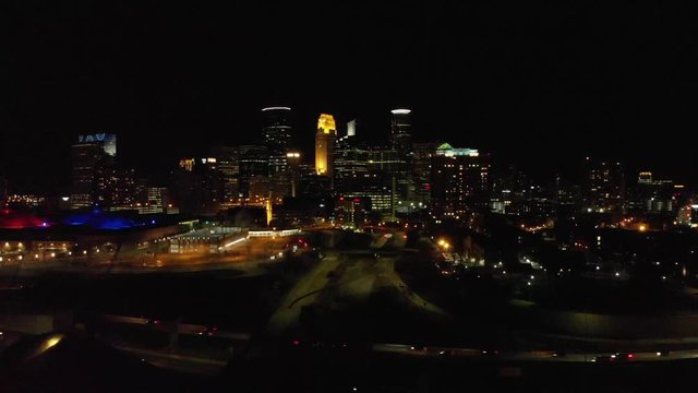 Aerial footage of downtown Minneapolis at night, traffic crossing by