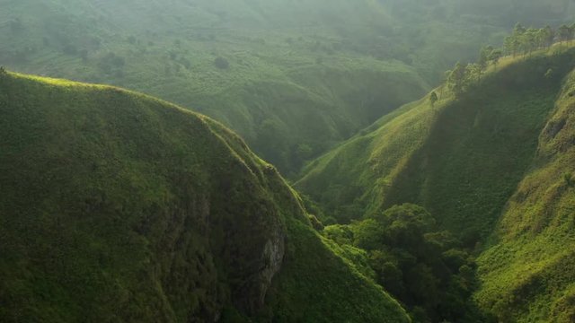 Aerial drone flyover shot of the green valleys and cliffs in the Karo Regency near Sipiso Piso in North Sumatra, Indonesia.