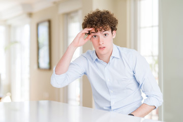 Young business man with curly read head worried and stressed about a problem with hand on forehead, nervous and anxious for crisis