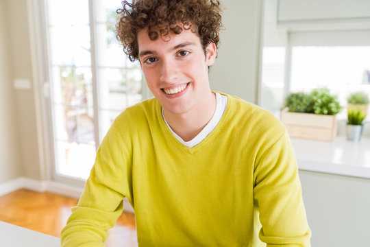 Young handsome man wearing yellow sweater at home with a happy and cool smile on face. Lucky person.