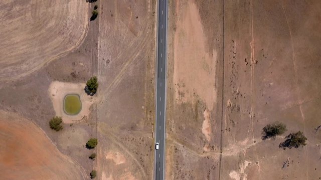 Bird view of white van in movement on straight road in desert