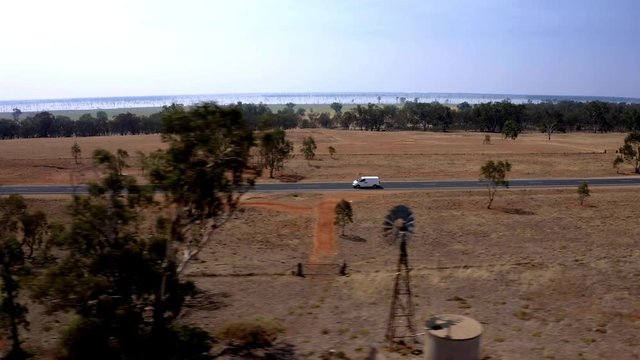 Side shot of a white van through trees on a road in a desert