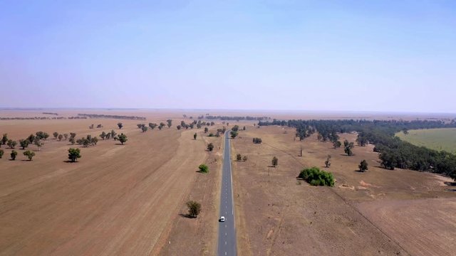 Medium to high angle of white van in movement on straight road in desert