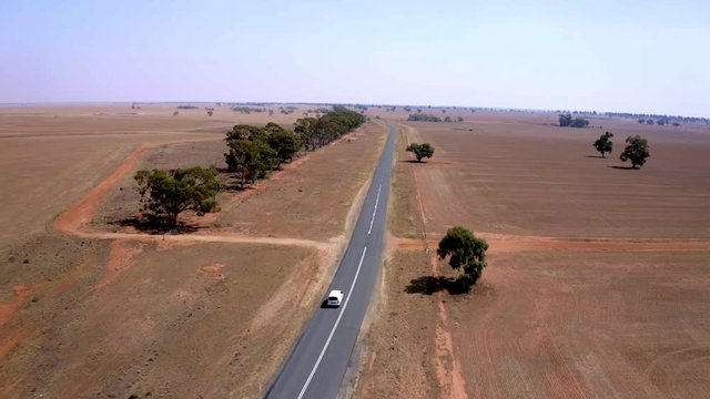 Tracking shot of a white van in movement on a road in a desert