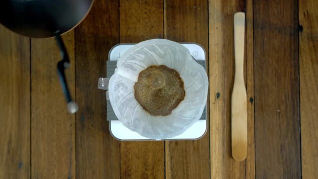 Man pouring water in a coffee filter and removing bubbles with spatula