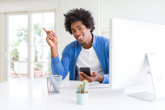 African American man working using smartphone and computer very happy pointing with hand and finger to the side