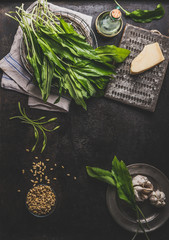 Food background with ramson, wild garlic, leaves bunch on dark rustic kitchen table with ingredients, top view. Healthy cooking still life. Spring seasonal food. Copy space