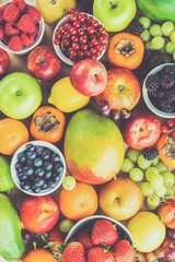 Fruit background, strawberries raspberries oranges plums apples kiwis grapes blueberries mango persimmon, top view, toned, selective focus