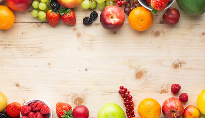 Fruits berries background, strawberries raspberries oranges plums apples kiwis grapes blueberries mango persimmon on the wooden table, top view, copy space for text, selective focus