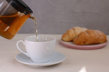 tea pouring in cup on light background. teapot and breakfast concept