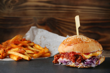 burger with cheese and vegetable and fries on rustic background