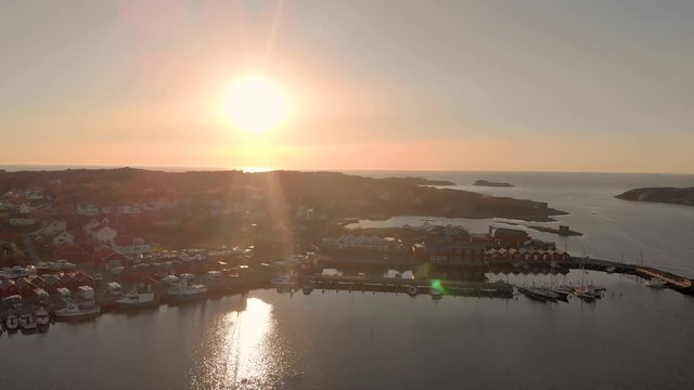 Drone flying towards small harbor in sunset