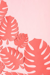 Fototapeta na wymiar Paper cut tropical leaves in dark coral colour on pink background, top view
