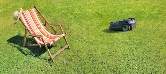 deckchair on greenery grass and robotic lawnmower on the grass