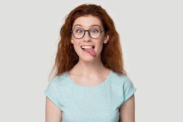 Obraz premium Funny red-haired girl in glasses play childish showing tongue
