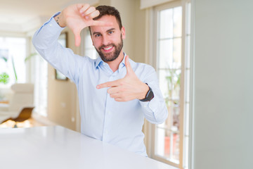 Fototapeta premium Handsome business man smiling making frame with hands and fingers with happy face. Creativity and photography concept.