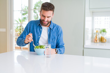Handsome man eating green peas at home