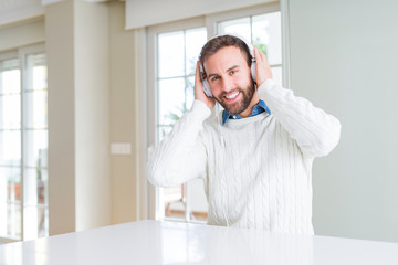 Fototapeta premium Handsome man wearing headphones and listening to music with a happy face standing and smiling with a confident smile showing teeth