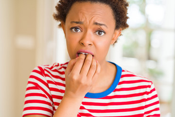 Fototapeta na wymiar Young beautiful african american woman at home looking stressed and nervous with hands on mouth biting nails. Anxiety problem.