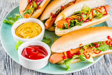 Homemade hot dogs with fresh greens, sausages and sauces, white wooden background copy space top view