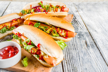 Homemade hot dogs with fresh greens, sausages and sauces, white wooden background copy space top view