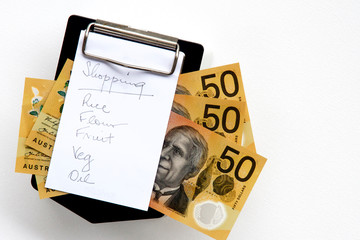 Shopping list on a clipboard with Australian fifty dollar notes.