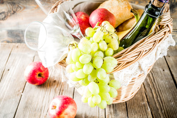 Picnic basket with food and drinks (fresh fruits, bread and wine bottle, glasses), copy space