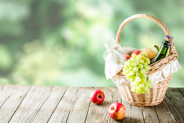 Picnic basket with food and drinks (fresh fruits, bread and wine bottle, glasses), copy space