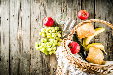 Picnic basket with food and drinks (fresh fruits, bread and wine bottle, glasses), copy space