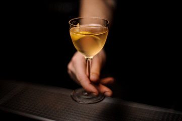 Close-up of alcohol cocktail with lemon rind in bartender's hand