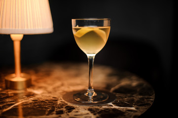 Close shot of an alcohol cocktail with lemon rind on table