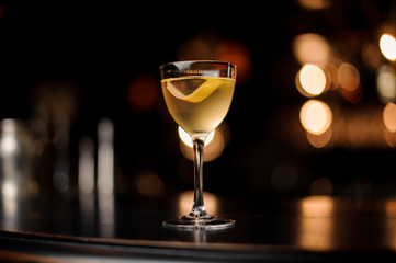 Close-up of the alcohol cocktail with lemon rind on counter
