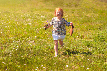 Happy young girl with a flower in his hand against the green grass