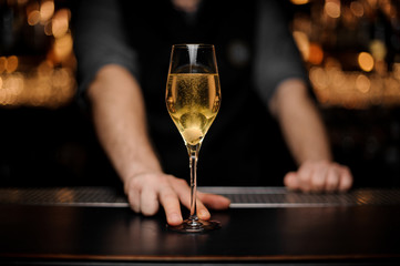 Close shot of glass with sparkling wine in the bartender's hands - obrazy, fototapety, plakaty
