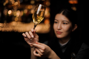 Close-up of bartender holding glass full of sparkling wine