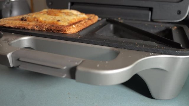 Cooked ham and cheese toasty is removed from the sandwich maker. LOCKED DOWN SHOT. CLOSE UP. WIDE ANGLE.
