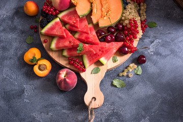 Fresh summer fruits and berries on a round cutting board, watermelon, cantaloupe, cherries, current © Sa Scha