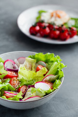 Healthy classical vegetable fresh salad of lettuce, tomato, cucumber, onion and sesame with olive oil dressing on white plate and white background. Diet menu.