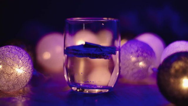 Nightlife footage of a gin tonic beverage in a lowballs rocks glass, sparkling, alcoholic drink, surrounded by a great atmosphere of lights.