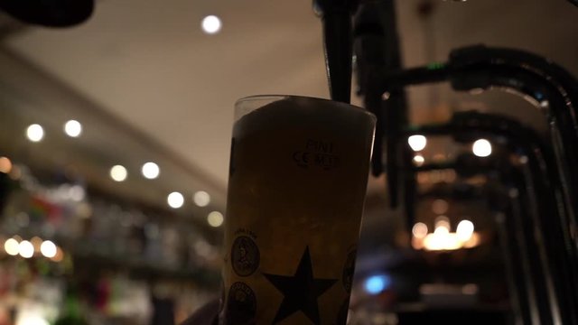 Low angle close up of a pint being pulled behind a bar