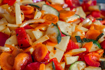 Raw fresh vegetables cut for further processing, mixed and topped with an oily spice mixture.