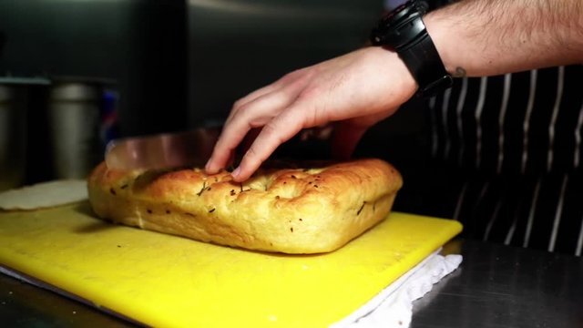 Tracking shot of chef cutting garlic bread